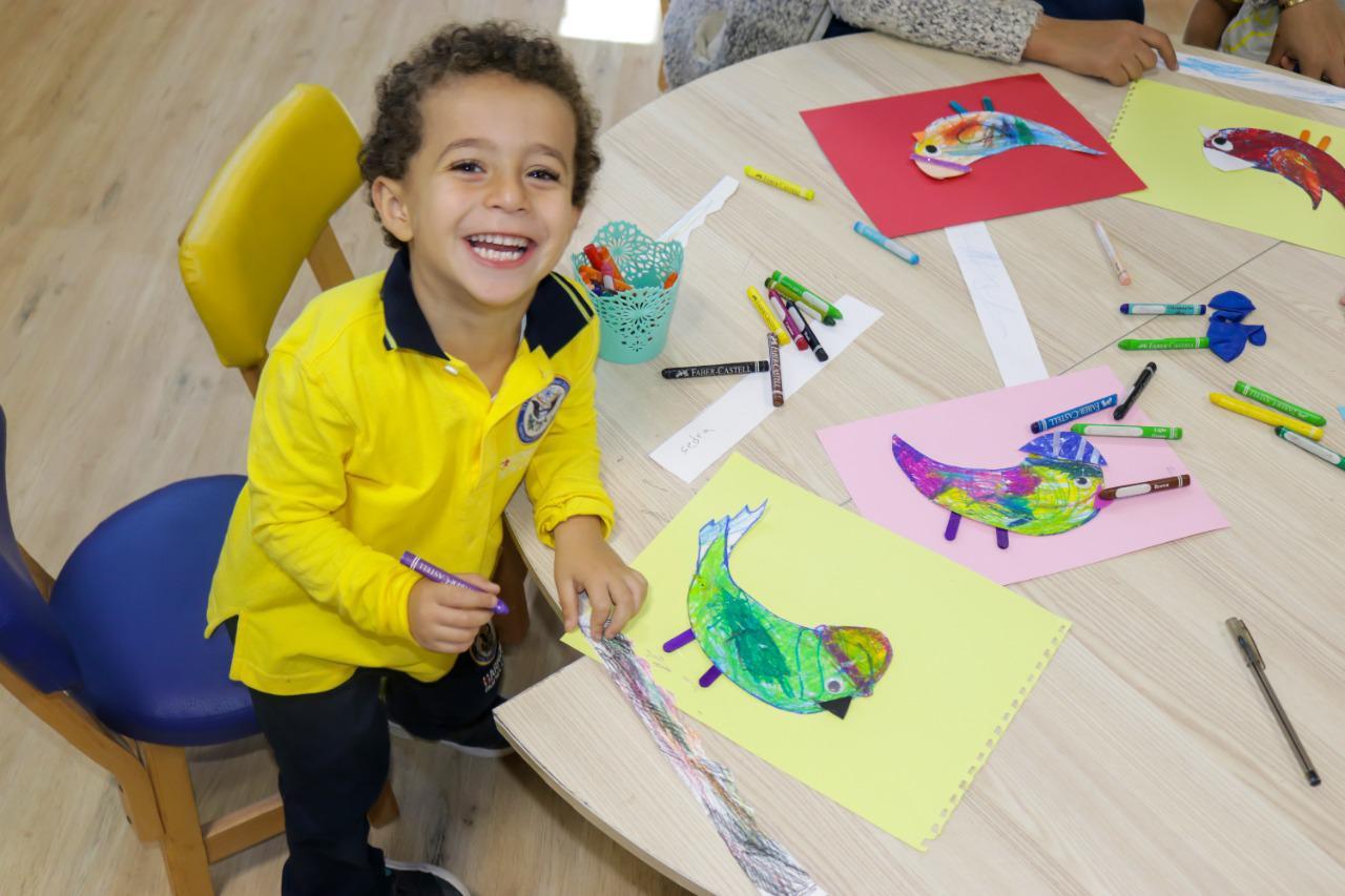 A young child at IVY STEM International School engaged in a creative art activity, surrounded by colorful drawings and materials. Experience the vibrant and joyful learning environment at our school.