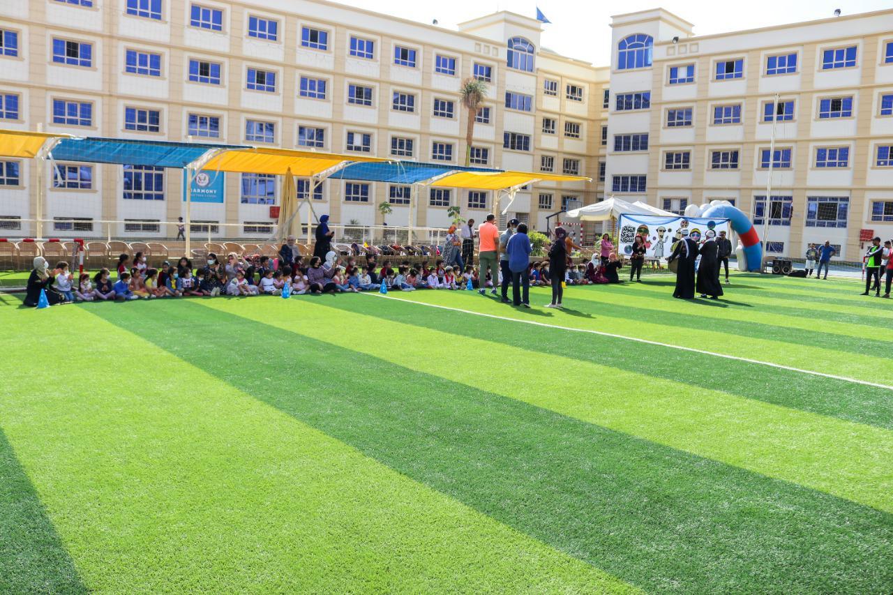Children gathered for an event or assembly at IVY STEM International School, with adults supervising and organizing the activities. The well-organized and supervised environment showcases a planned event or celebration, with a multi-storied cream-colored building in the background and a flagpole indicating an institutional facility.