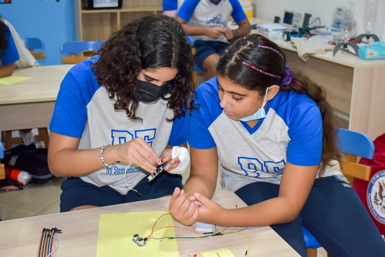 Two students from IVY STEM International School actively participating in a hands-on electronics project, learning about circuits and practical skills in a well-equipped classroom environment.